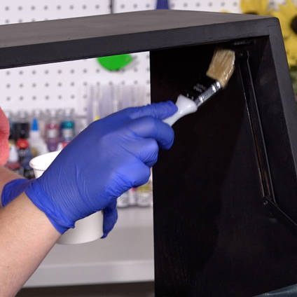 Brush applying resin to waterproof inside of bureau bar